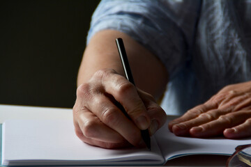 Notizen machen, Hand einer Frau schreibt in ein Heft, Nahaufnahme einer schreibenden Hand