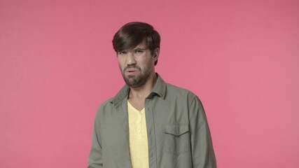 Man seeing disgusting thing. Handsome hispanic, bearded guy cringe, grimacing from aversion and dislike, pulling shocked startled face, look at embarrassing thing with discomfort, pink background