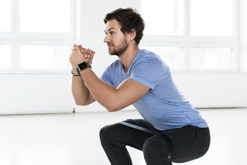 Man doing squats with a loop resistance band during workout in the gym