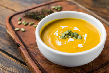 Pumpkin butternut squash cream soup in a bowl against wooden background