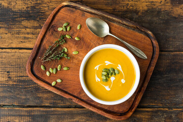 Pumpkin butternut squash cream soup in a bowl against wooden background