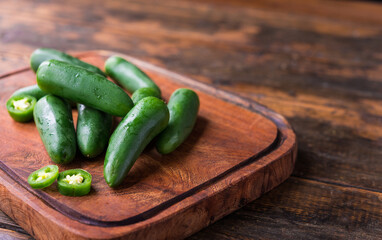 Spicy mexican jalapeno chili peppers against brown wooden background