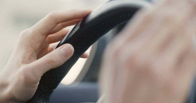 Female hands on a steering wheel tapping with music while driving.
