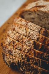 Close up view on freshly baked sourdough bread on wooden cutting board on bright backgrounda