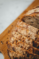 Close up view on freshly baked sourdough bread on wooden cutting board on bright backgrounda