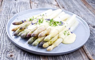 Traditioneller gekochter weißer Spargel mit violetten  Köpfen garniert Sauce Hollandaise und...