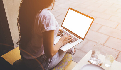 Rear view of young woman is using 5th generation wireless systems on net-book. Female freelancer is working on laptop computer with mock up blank copy space screen for your text message or content