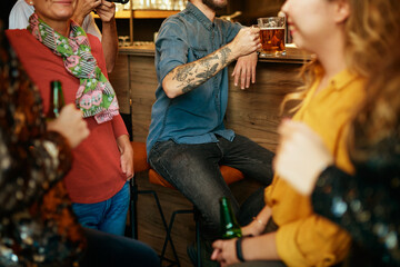 Group of friends hanging on in a pub, chatting and drinking beer.
