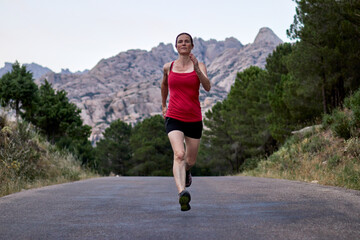Woman running down a road with the mountains in the background