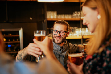 Group of friends hanging on in a pub, chatting and drinking beer.