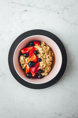 Close up view on oatmeal with strawberries and blueberries on bright textured table
