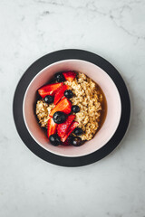 Close up view on oatmeal with strawberries and blueberries on bright textured table