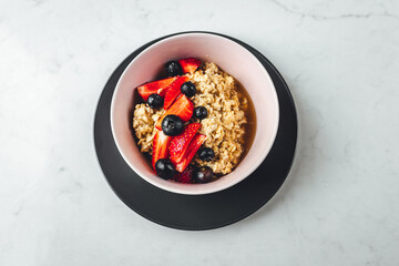 Close up view on oatmeal with strawberries and blueberries on bright textured table