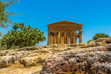 Fototapeta na wymiar The Temple of Concordia with a rocky outcrop in the foreground in the ancient Sicilian city of Agrigento in summer
