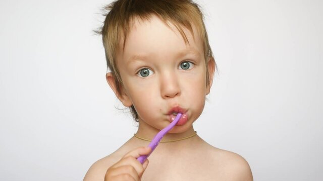 Close up of a beautiful little boy brushing his teeth against white background