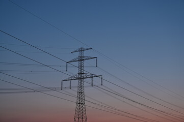 Dämmerung nach Sonnenuntergang mit rosa Himmel und Strommast mit Hochspannungsleitung (Elektrizität)