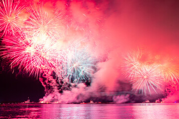 Holiday fireworks above water with reflection on the black sky background