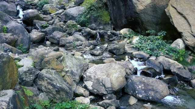 Waterfall passing through rocks and green vegetation. Footage shot at Jhalong, Dooars, West Bengal - India.