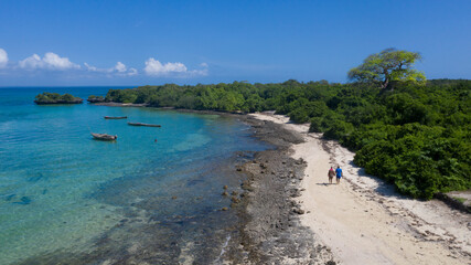 Drone view of a tourist couple walking down the beach on Kwale island in Zanizbar with physical distancing 