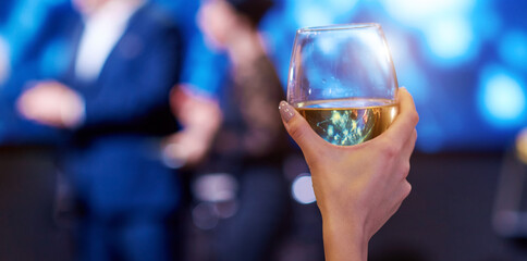 woman hand take up vine glass with persons blurred on background 