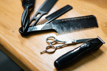 Scissors and clipper. Barber tools. Set of combs of a professional hairdresser. Black combs on a wooden table.