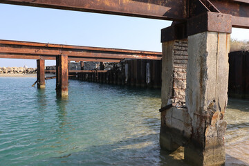 Old concrete support structures and rusting metal beams standing in clear blue Mediterranean water is all that remains of an old pier near Famagusta Northern Cyprus.