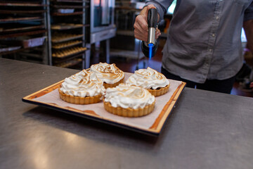 baker using a culinary torch to caramelize a pastry in a bakery