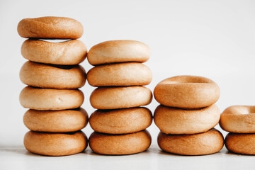 Drying or mini round bagels in the shape of a tower on a white wooden background. Copy, empty space for text