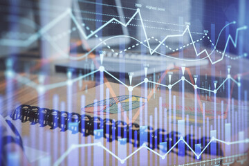 Double exposure of financial graph drawings and desk with open notebook background. Concept of forex market