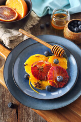 Citrus dessert. Orange carpaccio with honey, spices and blueberries from yellow and blood oranges