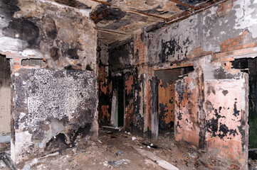 The interior of an abandoned building with rubbish on the floor, walls with peeling paint, a collapsed ceiling. 