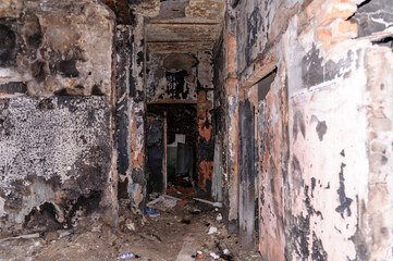 The interior of an abandoned building with rubbish on the floor, walls with peeling paint, a collapsed ceiling. 