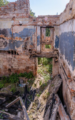 Abandoned ruined house, empty windows, charred walls, trash on the floor.