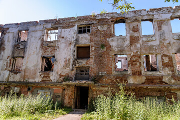 Abandoned ruined house, empty windows, charred walls, trash on the floor.