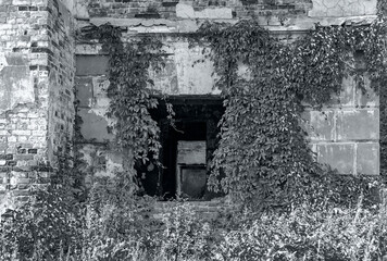 Abandoned ruined house, empty windows, charred walls, trash on the floor. Black and white photography.