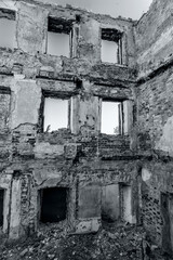 Abandoned ruined house, empty windows, charred walls, trash on the floor. Black and white photography.