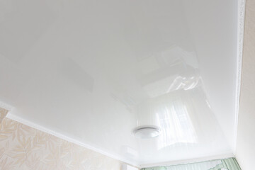 Glossy white ceiling in the interior of the bedroom