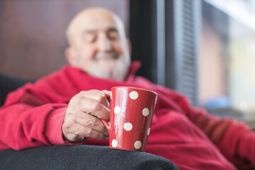 old man sitting in an armchair and drinking tea