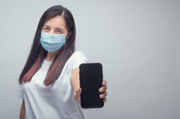 Woman portrait in inspirational mood with face mask and cell phone message, physycal distancing.