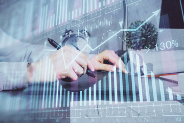 Double exposure of man's hands holding and using a phone and financial graph drawing. Analysis concept.