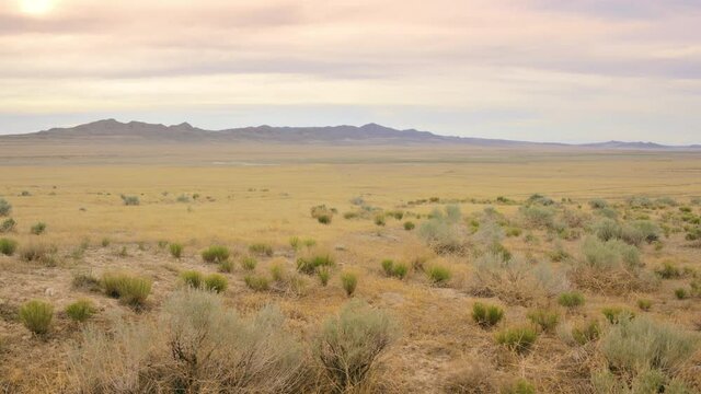 Pan across a vast overcast desert plain with a distant road