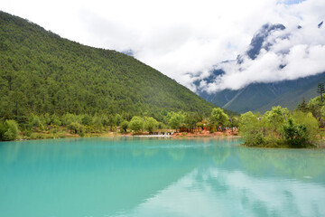 Fototapeta premium green lake have reflection of the mountain under the white clouds