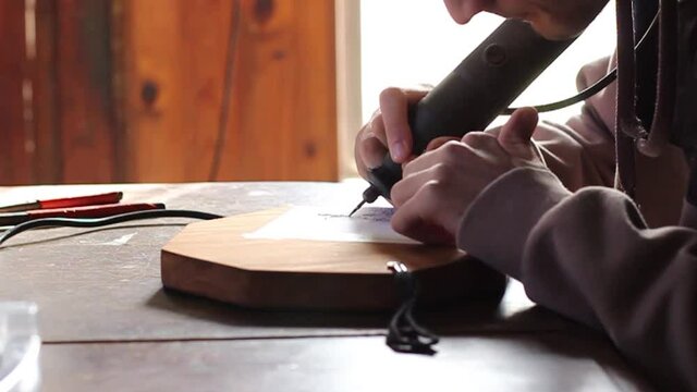 young man carving figures on wood