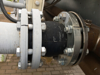 Old grey painted rubber expansion joint with cracks in the pipeline in industrial production line.