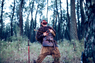 Red-bearded Viking in suit and blood-filled leather armor from a battle in the middle of the forest - 361437861