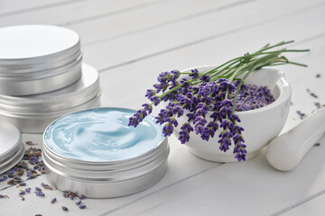 Natural organic lavender cream, mortar and bunch of dry lavender flowers on white wooden table.