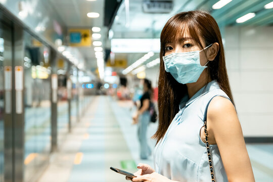 Business Woman Wearing Face Mask At Train Station Using The Mobile Phone