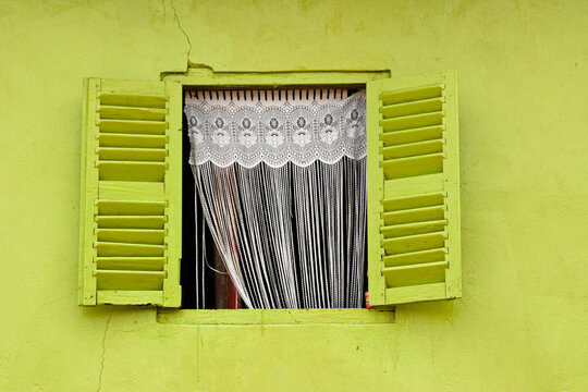 Lace curtains in window of colorful house, Axim, Ghana