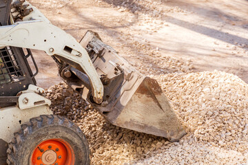 Russia Samara April 2020: Utility tractor Mini loader Bobcat S175 rakes gravel during repair of...