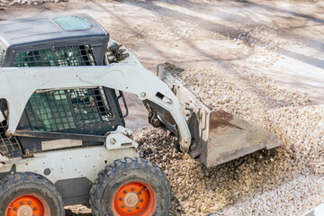Russia Samara April 2020: Utility tractor Mini loader Bobcat S175 rakes gravel during repair of...